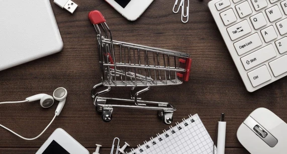 Carrello della spesa in miniatura su scrivania: simbolo di e-commerce, acquisti online e logistica veloce