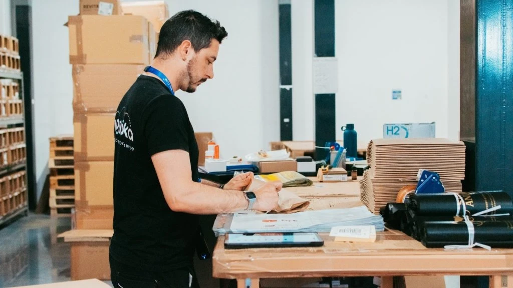 Operatore Momoka prepara un ordine eCommerce alla postazione di imballo in magazzino