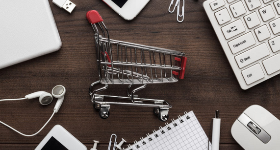 Carrello della spesa in miniatura su scrivania: simbolo di e-commerce, acquisti online e logistica veloce