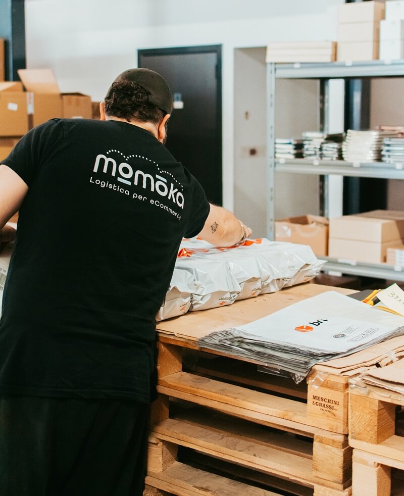 Operatore Momoka impegnato nella gestione e sistemazione dello stock all'interno di un magazzino per eCommerce organizzato strategicamente.