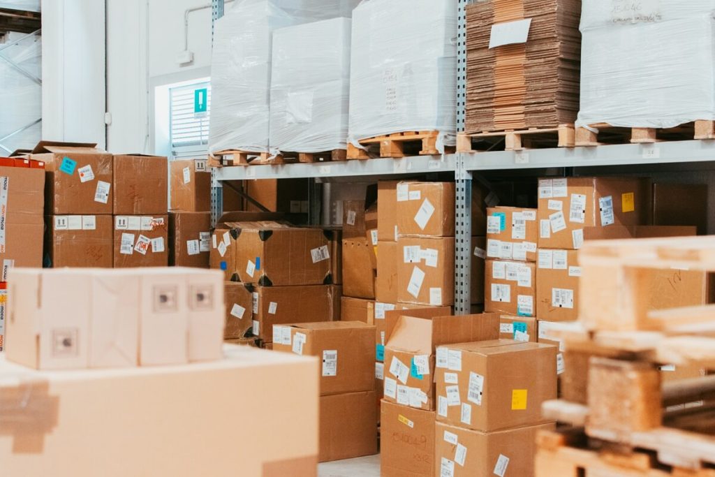 Vista ravvicinata di scaffalature industriali piene di scatole di cartone e bancali imballati in un magazzino logistico, a dimostrazione della corretta ottimizzazione degli spazi di stoccaggio e delle scorte.