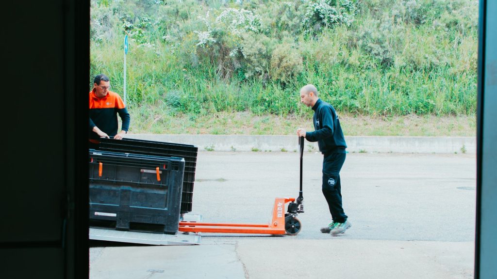 Operatore Momoka porta un pallet fuori dal magazzino per il carico sul corriere